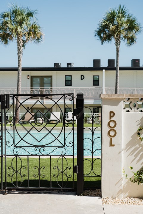 A pool with a black fence and a white pillar with the word POOL on it at The PARKER on E Mulberry Apartments, San Antonio, TX