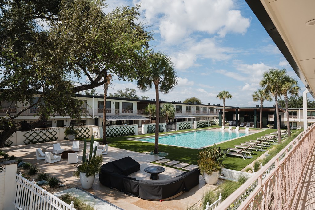 A pool area with lounge chairs and a white fence at The PARKER on E Mulberry Apartments, San Antonio, TX, 78209