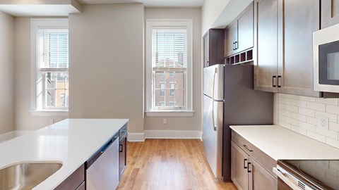 A kitchen with a refrigerator, sink, and cabinets.