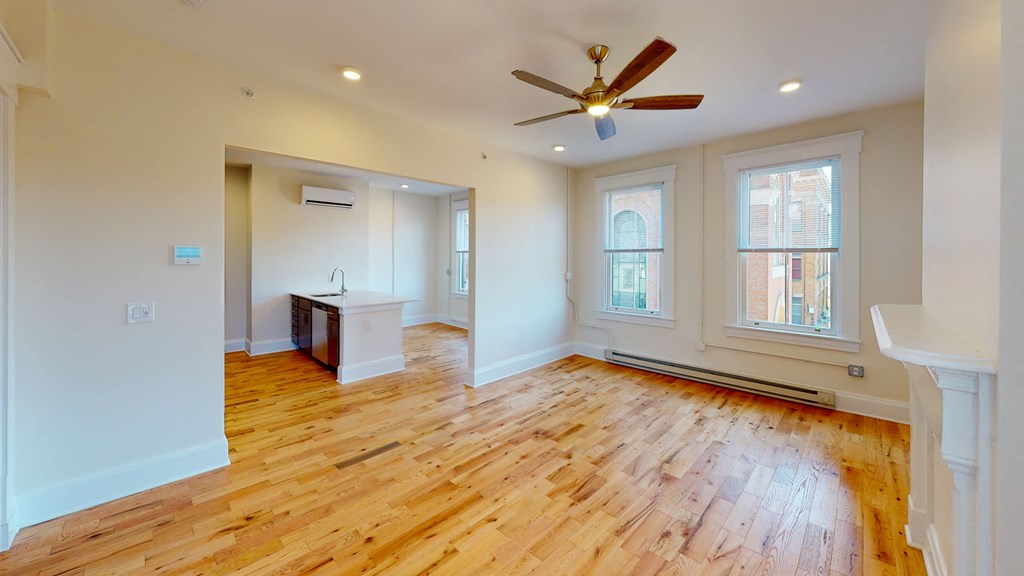 an empty living room with wood floors and a ceiling fan