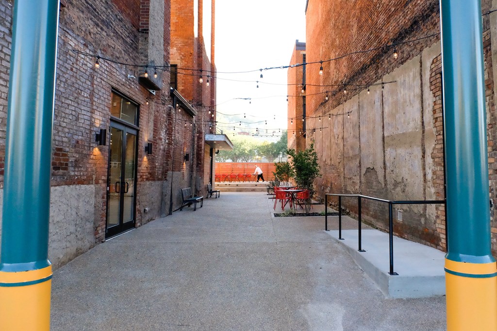 an empty alleyway between two brick buildings with a person walking in the distance