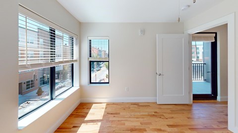 A room with a wooden floor and a window with blinds.