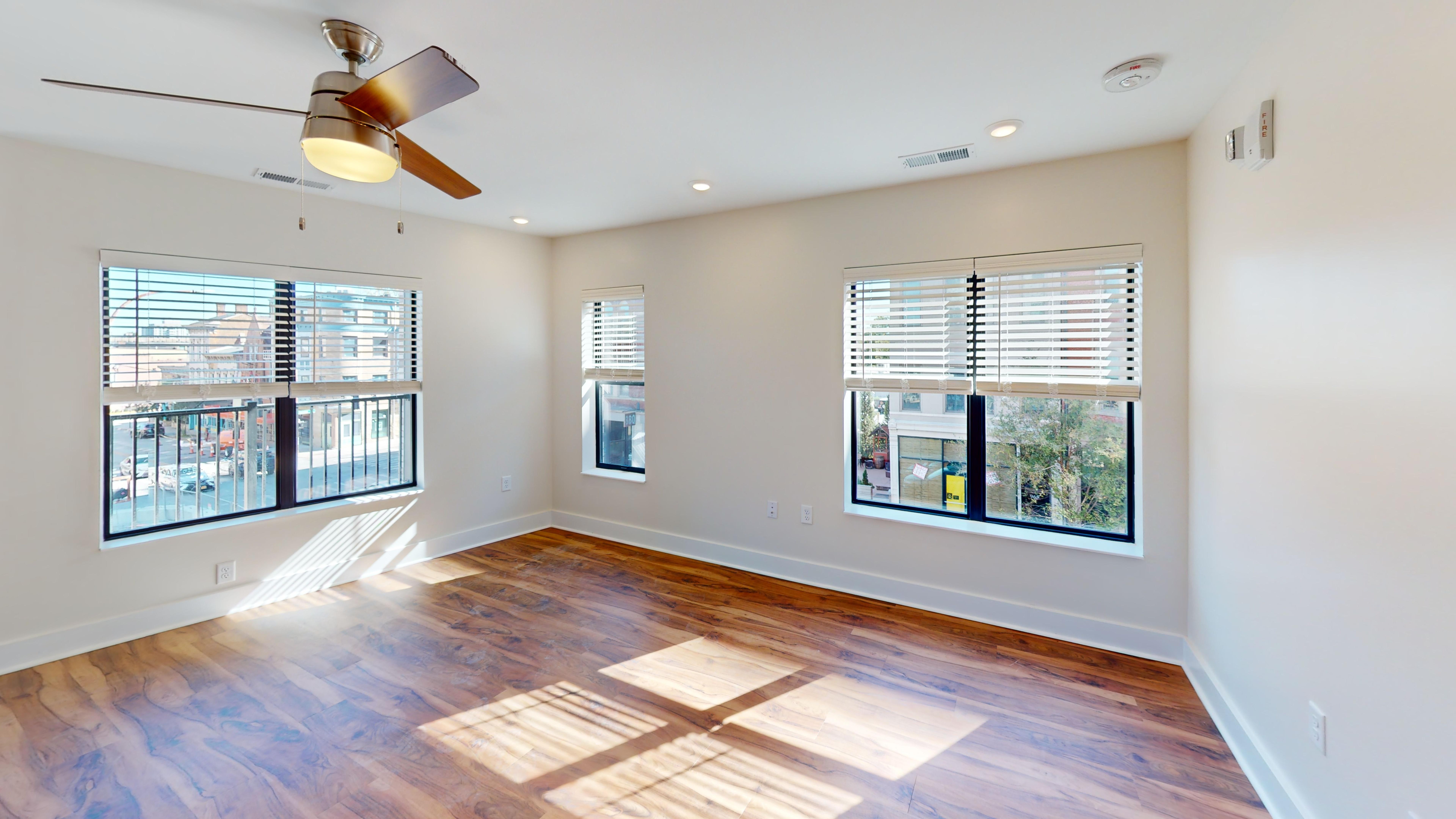 A room with a ceiling fan and wooden flooring.