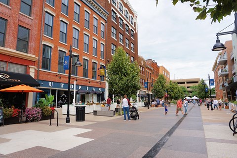 A city street with people walking and a red umbrella.