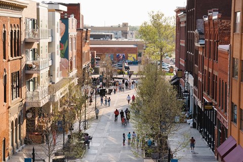 A city street with people walking and trees.