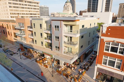 A busy street scene with people sitting at outdoor tables.