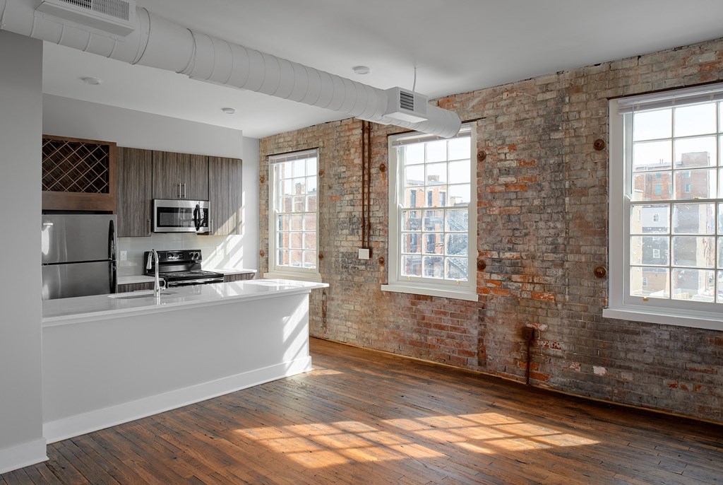 an empty room with a kitchen and a exposed brick wall