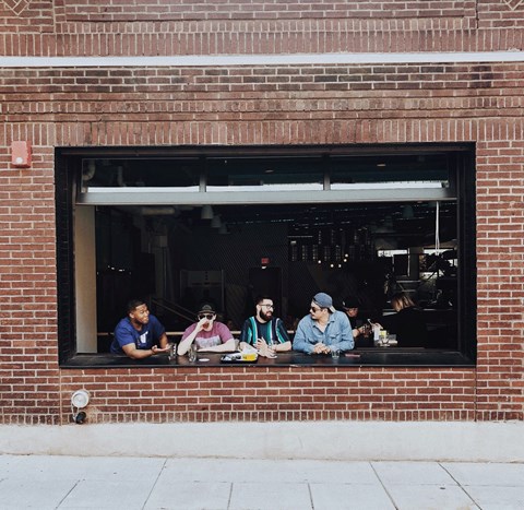 a group of people sitting in a window of a brick building