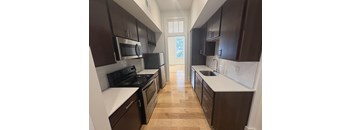 A kitchen with dark brown cabinets and a white counter.