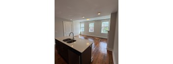 A kitchen with a sink and wooden floors.