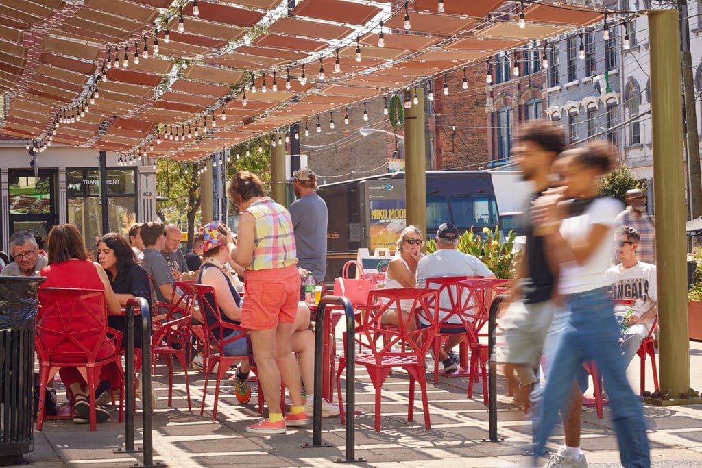A busy outdoor restaurant with people sitting at tables and enjoying their meals.