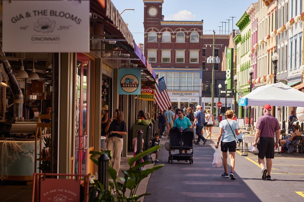 A street scene with people walking and a sign that says "MOTHER'S DAY".