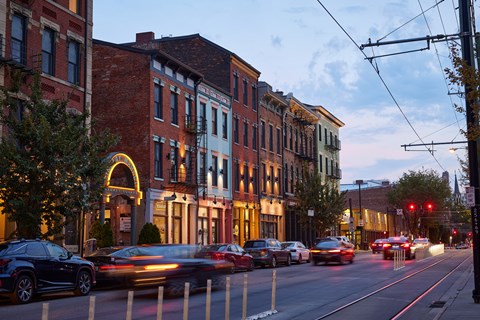 Cars are driving down a street lined with buildings.