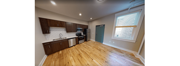 A kitchen with wooden floors and a white brick backsplash.