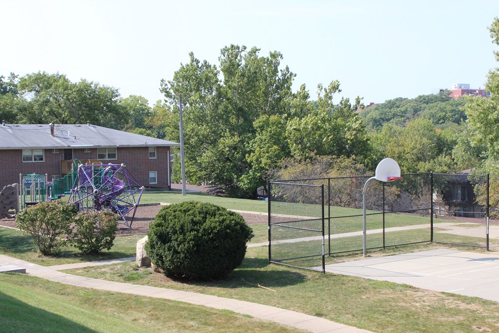 a playground with a basketball hoop and basketball hoop in front of a brick building