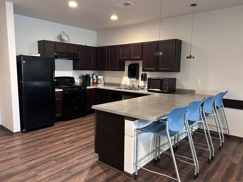 A kitchen with dark wood floors and white walls.