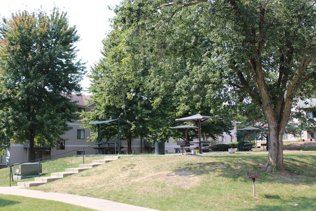 a grassy area with trees and buildings in the background