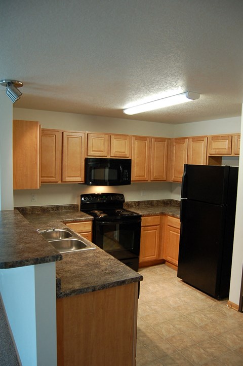 a kitchen with wood cabinets and black appliances