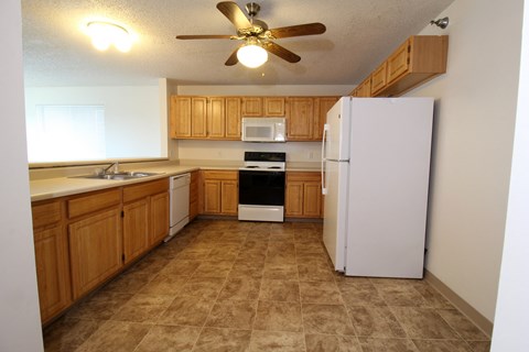 A kitchen with a white refrigerator and wooden cabinets.