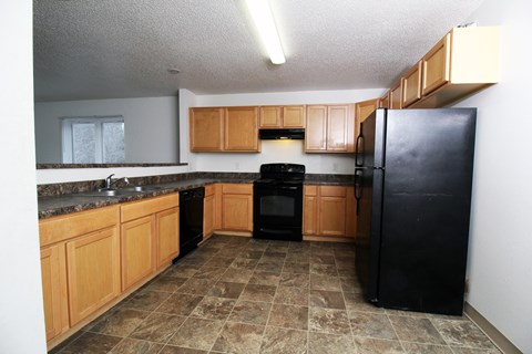 A kitchen with black appliances and wooden cabinets.
