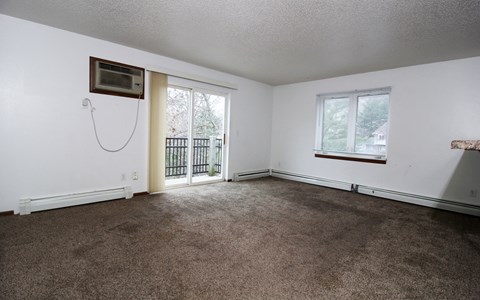 an empty living room with carpet and a balcony