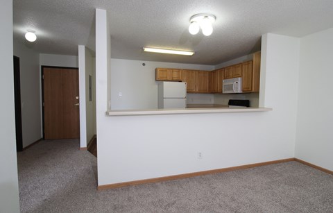 an empty living room and kitchen with a white wall