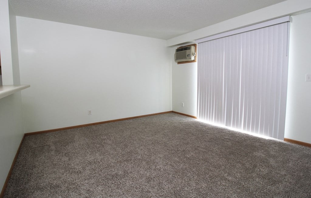 a bedroom with a large window and a carpeted floor