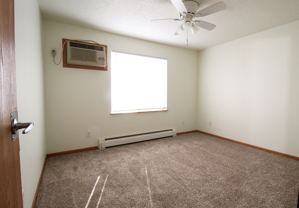 an empty room with a ceiling fan and a window