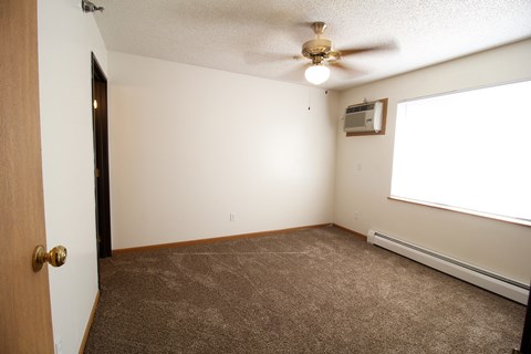 an empty room with a ceiling fan and a window