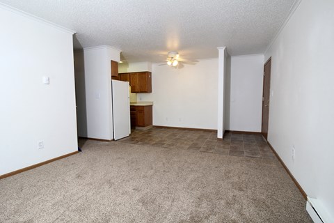 an empty living room with white walls and a kitchen