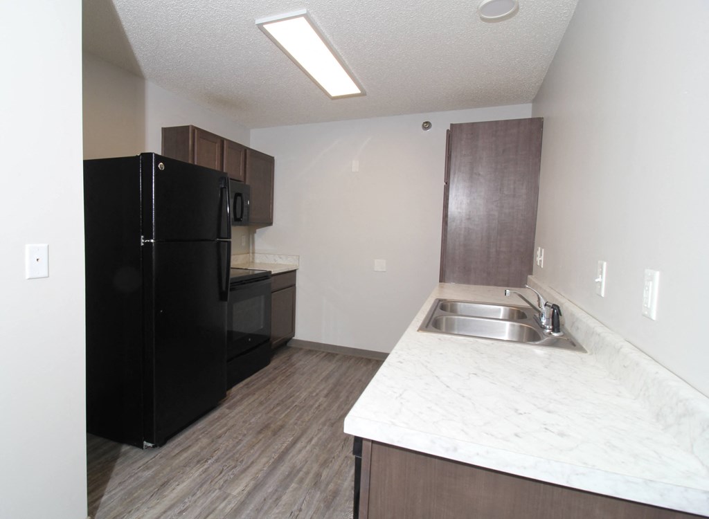 a kitchen with a black refrigerator freezer and a sink