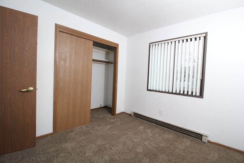an empty room with a door open to a closet and a window