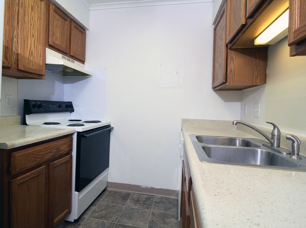 a kitchen with wooden cabinets and a white stove top oven