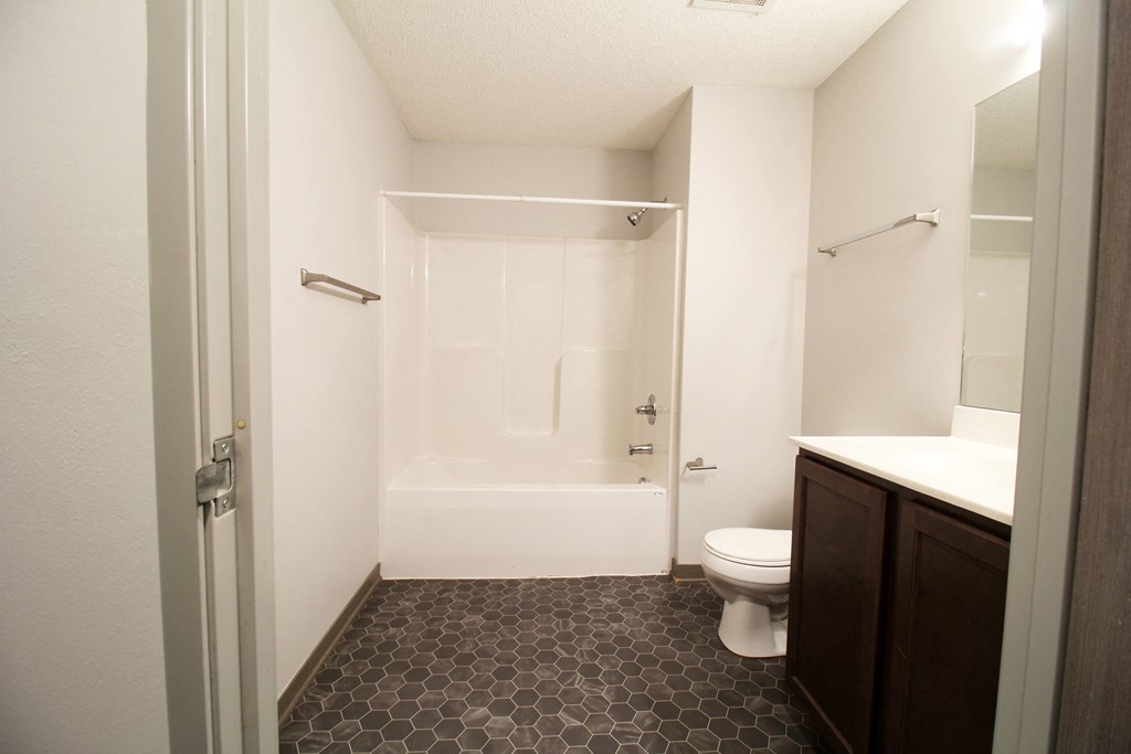 a bathroom with a white toilet next to a white bathtub