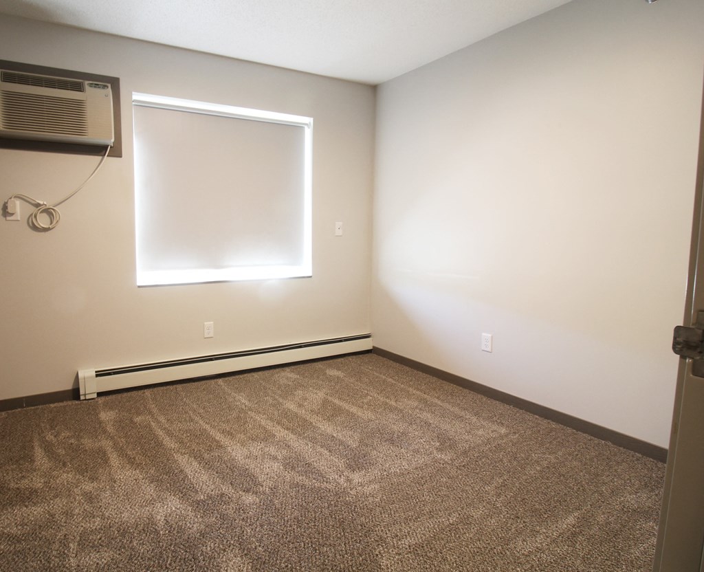 an empty room with a window and an air conditioner
