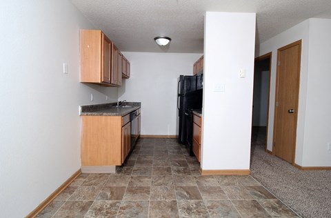A kitchen with a black fridge and wooden cabinets.