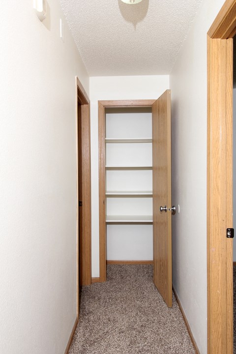 a small hallway with a wooden door and a carpeted floor