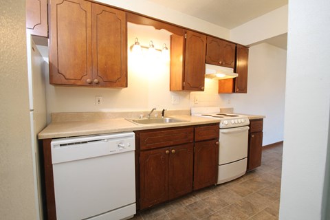 A kitchen with white appliances and wooden cabinets.
