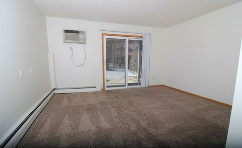 A room with a carpeted floor and a window with blinds.