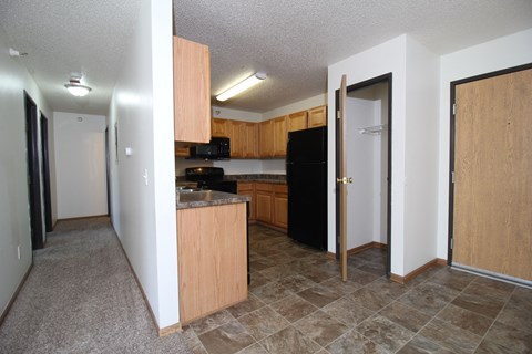 A kitchen with a black refrigerator and wooden cabinets.