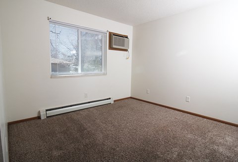 an empty room with a window and an air conditioner