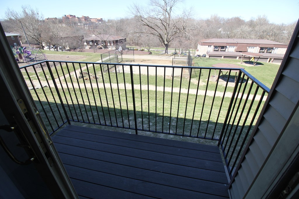 a balcony with a fence and a park in the background