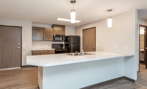A kitchen with a marble countertop and wooden cabinets.
