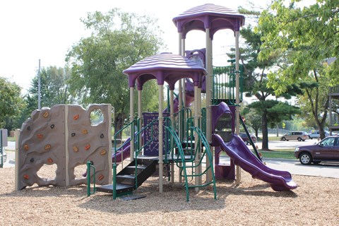 A playground with a purple slide and climbing wall.