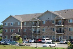A large apartment building with cars parked in front.