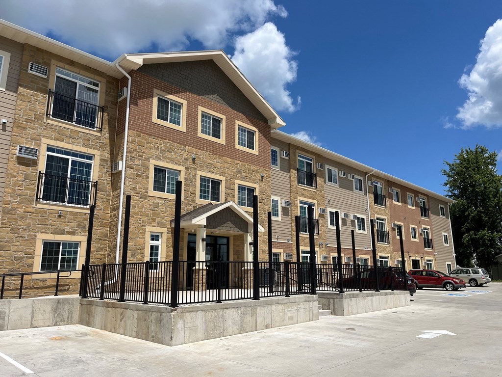 a three story apartment building with cars parked outside
