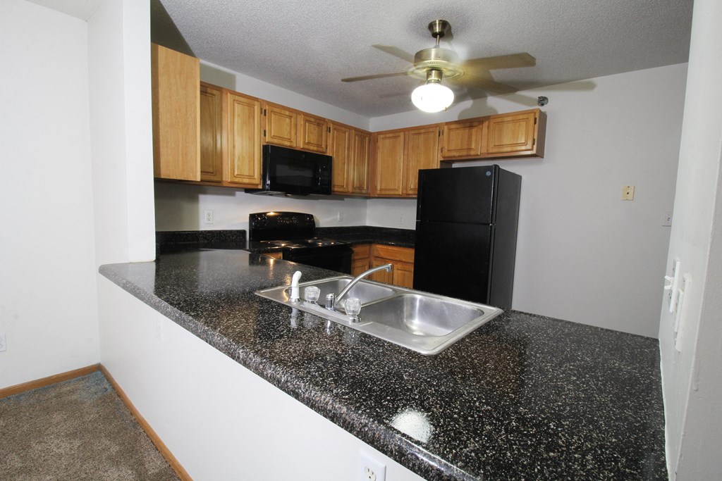 a kitchen with granite countertops and black appliances