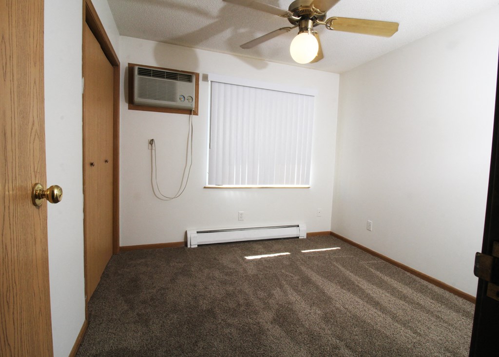 an empty bedroom with a ceiling fan and an air conditioner