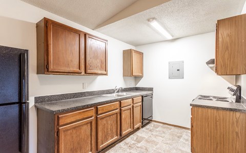 A kitchen with wooden cabinets and a black refrigerator.