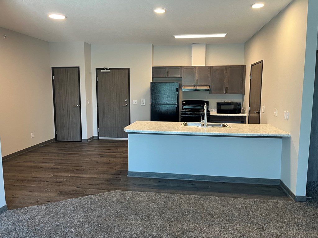 a kitchen and living room with a blue island and a black refrigerator